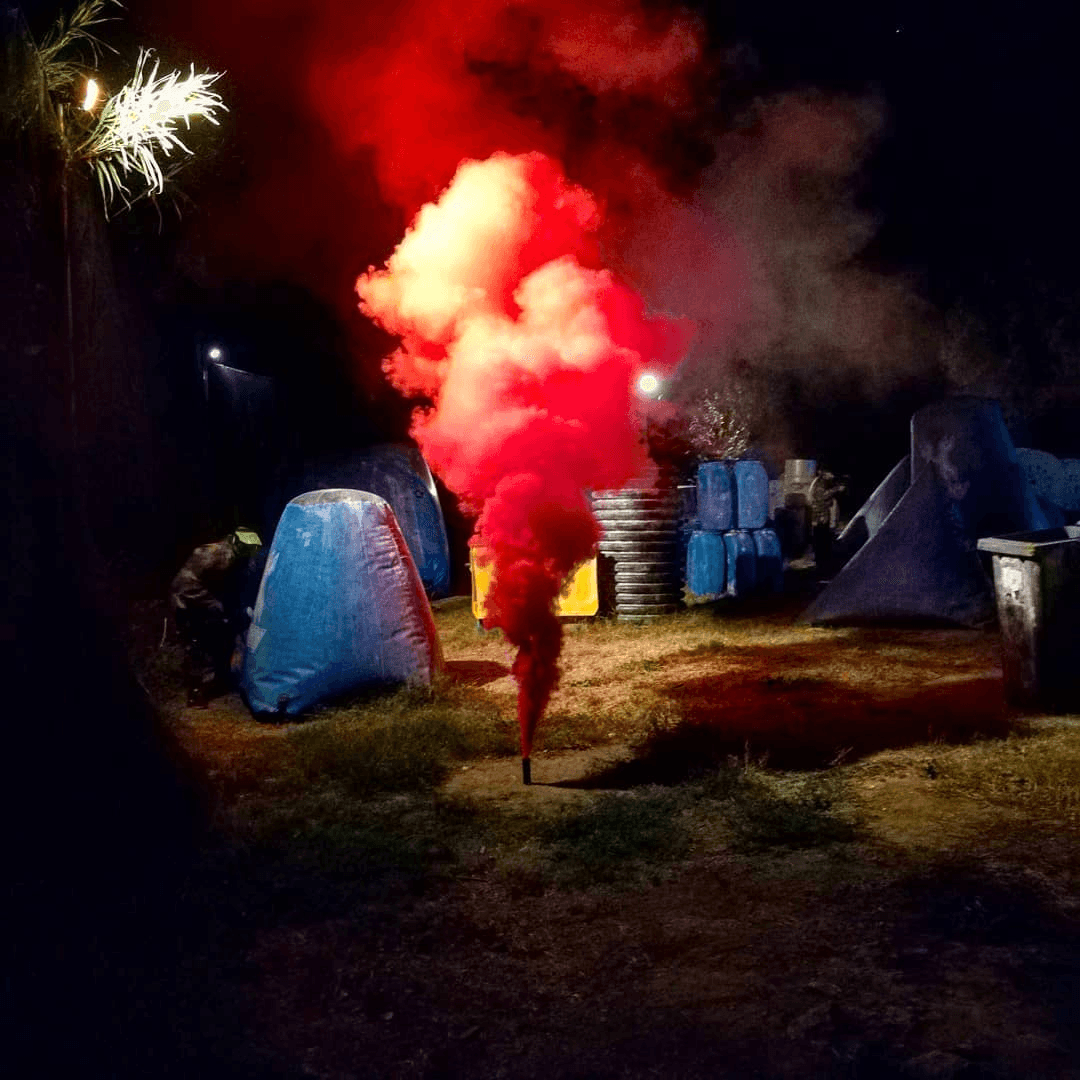 Scène nocturne paintball avec fumigène rouge sur le terrain